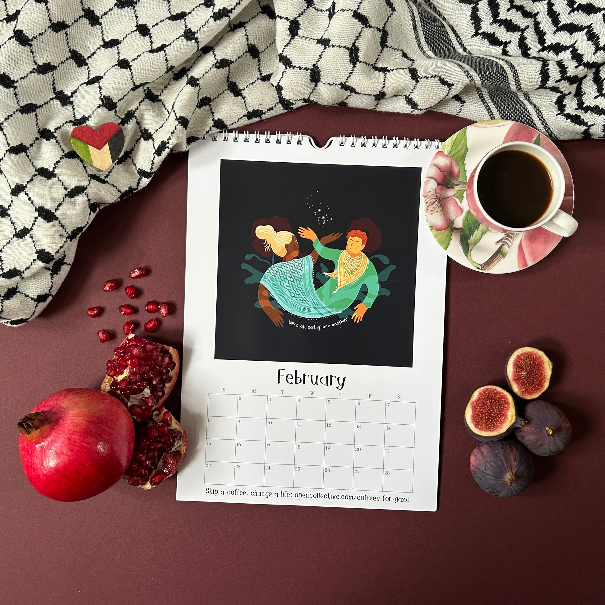 Calendar with an illustration of two intertwined people on a table with a cup of coffee, figs, and pomegranates.