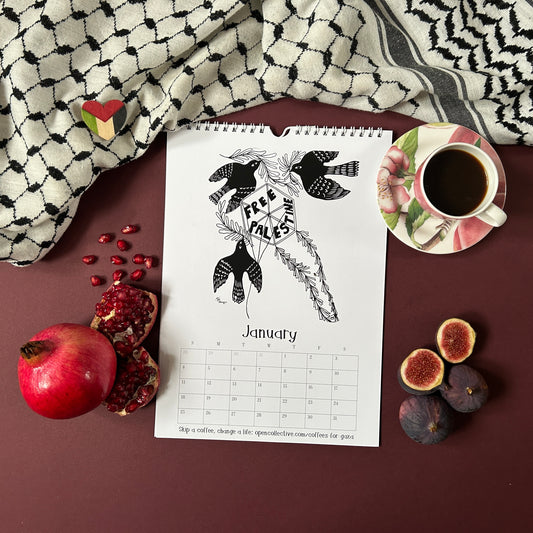 Calendar with January page featuring a traditional Kite and the lettering free Palestine, cup of coffee, figs, and pomegranate on a keffiyeh